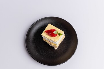 Delicious piece of white Shortcake on a black plate, decorated with fresh red strawberries