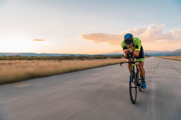  Triathlete riding his bicycle during sunset, preparing for a marathon. The warm colors of the sky...