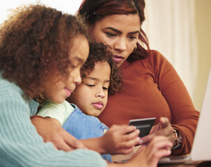 Choosing outfits for the girls. an attractive young woman sitting with her daughters at home and using a laptop for online shopping.