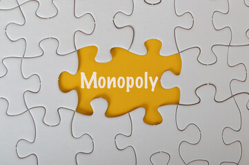 Fototapeta premium Missing jigsaw puzzle with text MONOPOLY isolated on a yellow background.