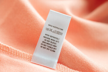 White laundry care washing instructions clothes label on pink cotton shirt