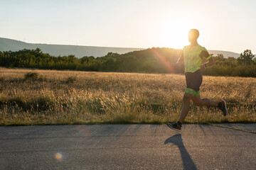 Triathlete in professional gear running early in the morning, preparing for a marathon, dedication...
