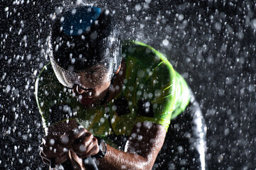 A triathlete braving the rain as he cycles through the night, preparing himself for the upcoming...