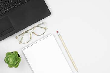 Working space with blank notepad, pencil, glasses, laptop and plant. Top view 