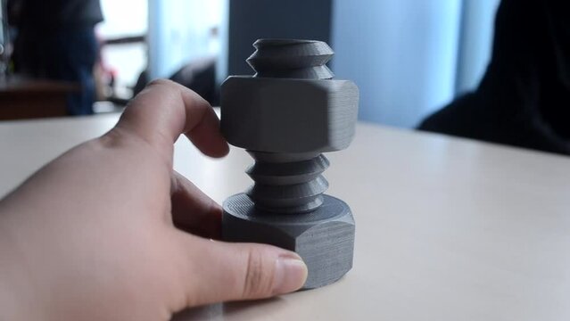 Person twisting with finger nut on plastic bolt printed on 3D printer. Models printed on 3D printer. Technology FDM. New modern additive technologies. Concept of creating prototypes on 3D printer