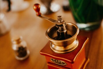 Vintage coffee grinder on a wooden table next to coffee beans on the table © Jonathan Borba/Wirestock Creators