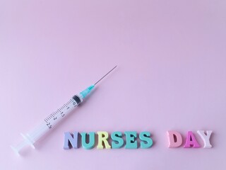 A syringe on a pink background and the words nurses day Concept of nurses day