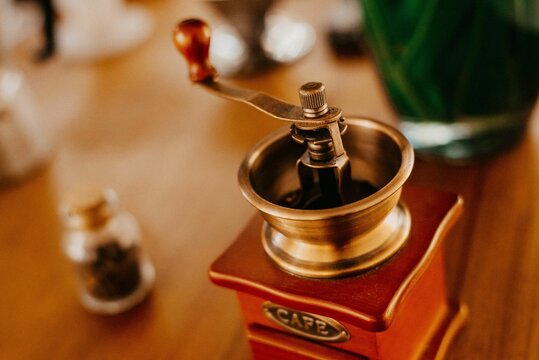 Vintage coffee grinder on a wooden table next to coffee beans on the table