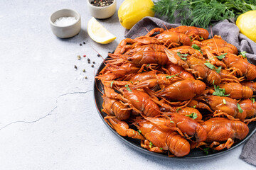 top view of cooked crawfish platter with lemons and spices on cement background