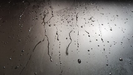 Water drops on a black plastic. Surface with wet background. Abstract texture and pattern full of water. Raindrops of rain for overlaying on window with partial focus. Concept of autumn weather