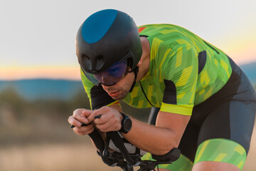  Close up photo of triathlete riding his bicycle during sunset, preparing for a marathon. The warm...