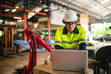 Professional engineer holding robot controller checking and repairing automatic robotic machine at industrial factory, Technician worker working with robotic arm system for manufacturing production