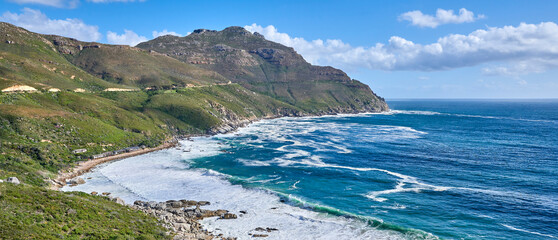 Fototapeta premium A photo of mountains, coast and ocean from Shapmanns Peak,. A photo mountains, coast and ocean from Shapmanns Peak, with Hout Bay in the background. Close to Cape Town.