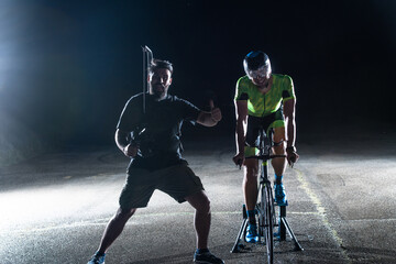 Behind the scenes. Professional videographer on a night shoot with a triathlete riding a bicycle...