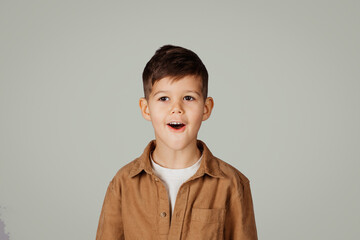 Positive inspired surprised cute little kid 6 years old in shirt look at camera, isolated on gray...