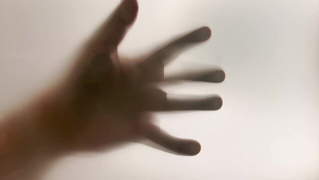 A mysterious hand slams on a frosted window then slowly falls.  	