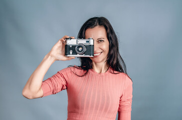 Slender woman holds an old film camera in her hands, takes pictures