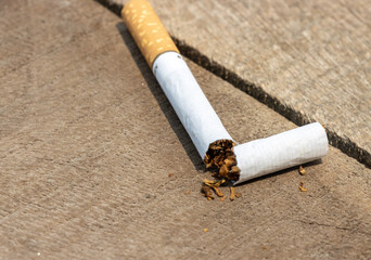 Broken cigarette close-up on a wooden table. No smoking or anti-smoking movement. A cigarette is...