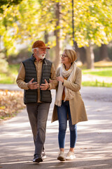 Cheerful pensioners enjoying their life walking together in the park and talking. Activities for...