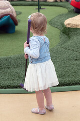 Young girl toddler playing mini golf with her dad