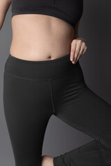 Studio product photo of grey yoga pants. They are being worn by a caucasian woman who is unidentifiable. The background is grey. 