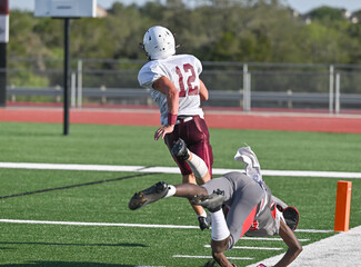 Young athletic young boys playing in a competitive game of tackle football and making incredible...