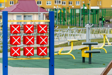Fototapeta na wymiar A modern outdoor playground in the courtyard of a building. Colorful children's swings and slides for recreation and games are installed. Playground on the background of residential buildings.