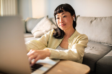 Fototapeta premium Young Japanese Woman using a laptop on a couch