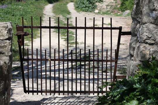 Vielle porte en fer rouillé donnant accès à un chemin