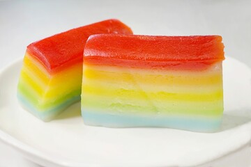 A closeup shot of 2 slices of Rainbow Kueh Lapis, a colorful variant of the traditional Nyonya snack