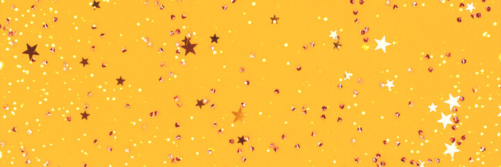 Banner with glowing golden stars and crystals confetti on a yellow background. Festive composition. Selective focus.