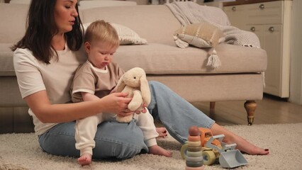 Happy family at home. Mother and baby boy playing with toys at home indoors. Little toddler child and babysitter nanny having fun together. Young woman mom kid son rest in living room