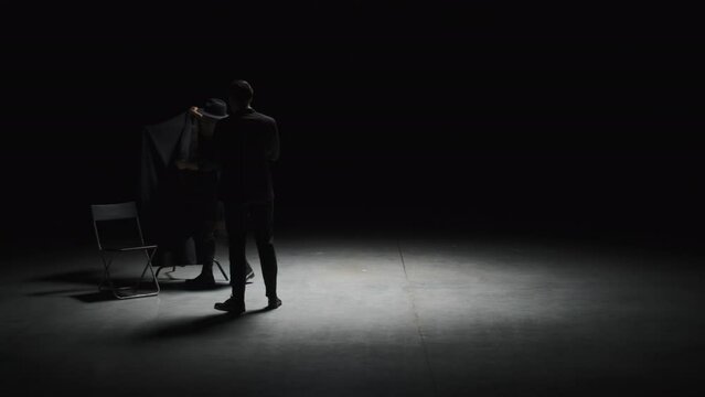 Theatrical production in dark room. Stock footage. Funeral on theater stage with actors. Theatrical staging of funeral in dark room with actors and props
