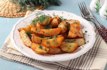 Baked potatoes with paprika sprinkled with dill in white plate on blue background