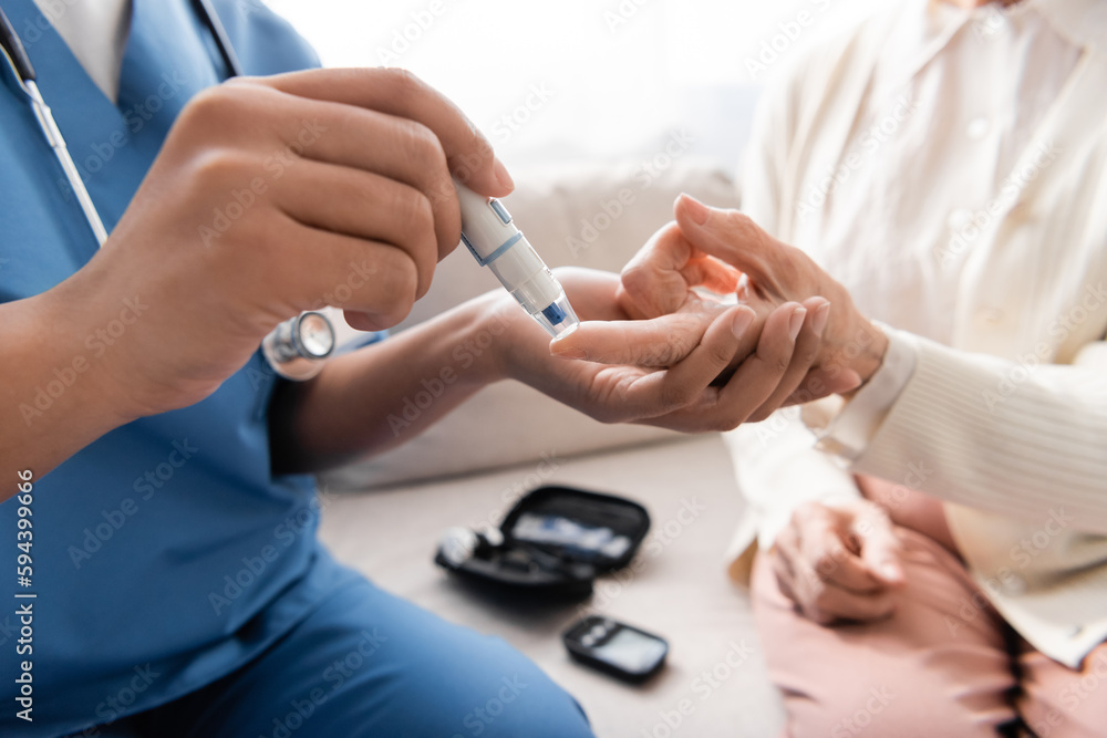 Wall mural cropped view of multiracial nurse taking blood sample of senior woman with lancet pen.