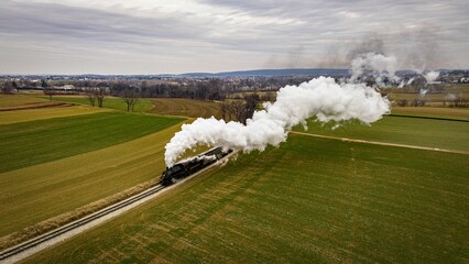Vintage locomotive train chugging along railroad tracks in a scenic countryside setting