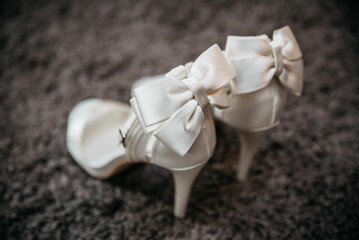 a pair of white high heels with bows tied down and a heelless shoe