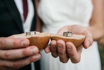 a couple holding wedding rings at their engagement ceremony in the park