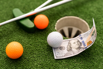 Mini Golf club, ball and money on the artificial grass