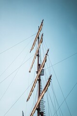 A vertical shot of a ship mast with a blue sky in the background