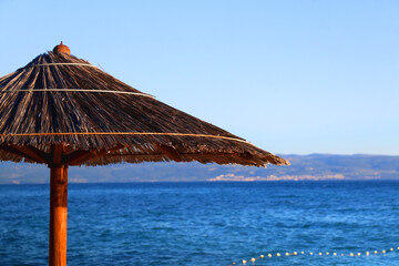 Bamboo parasol on the beach. Bright blue sky and sea in the background. Selective focus.