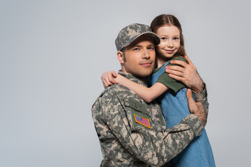 happy girl hugging father in military uniform during memorial day isolated on grey.