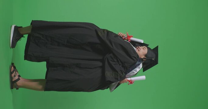 Full Body Of Asian Woman Students Graduate In Caps And Gowns Hugging Each Other, Smiling, And Showing Diplomas In Their Hands To Camera On The Green Screen Background In The Studio
