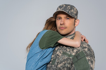 girl hugging father in military uniform during memorial day isolated on grey.