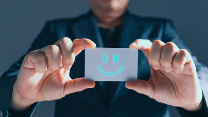 a businessman holding card on the happy smile face icon to give satisfaction in service.rating very impressed.customer service and satisfaction concept.