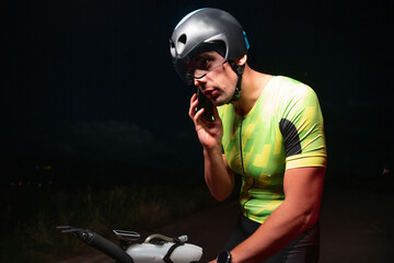 A triathlete using a smartphone while taking a break from a hard night's cycling training