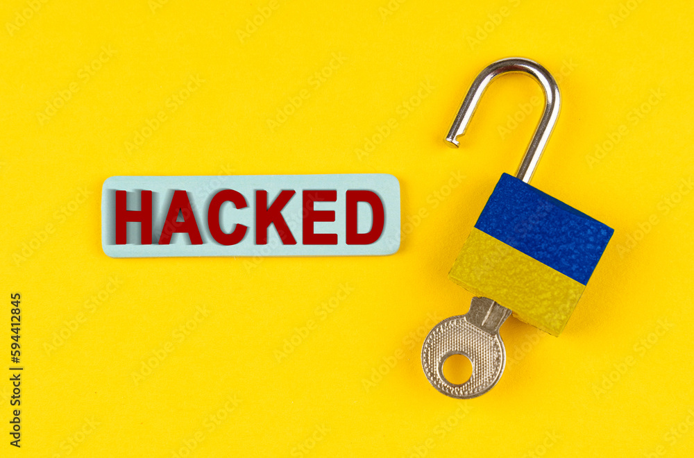 Poster on the yellow surface is an open lock with a key and a sticker with the inscription - hacked