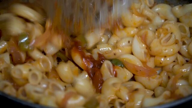 Closeup shot of adding chilly sauce while cooking. Adding flavour while cooking pasta.