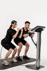 EMC group training. Trainer shows girl in EMC suit physical exercises. Sport group training in...