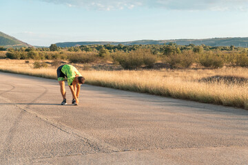 In the early morning light, the triathlete preparing for run by tying his shoes. With focused...
